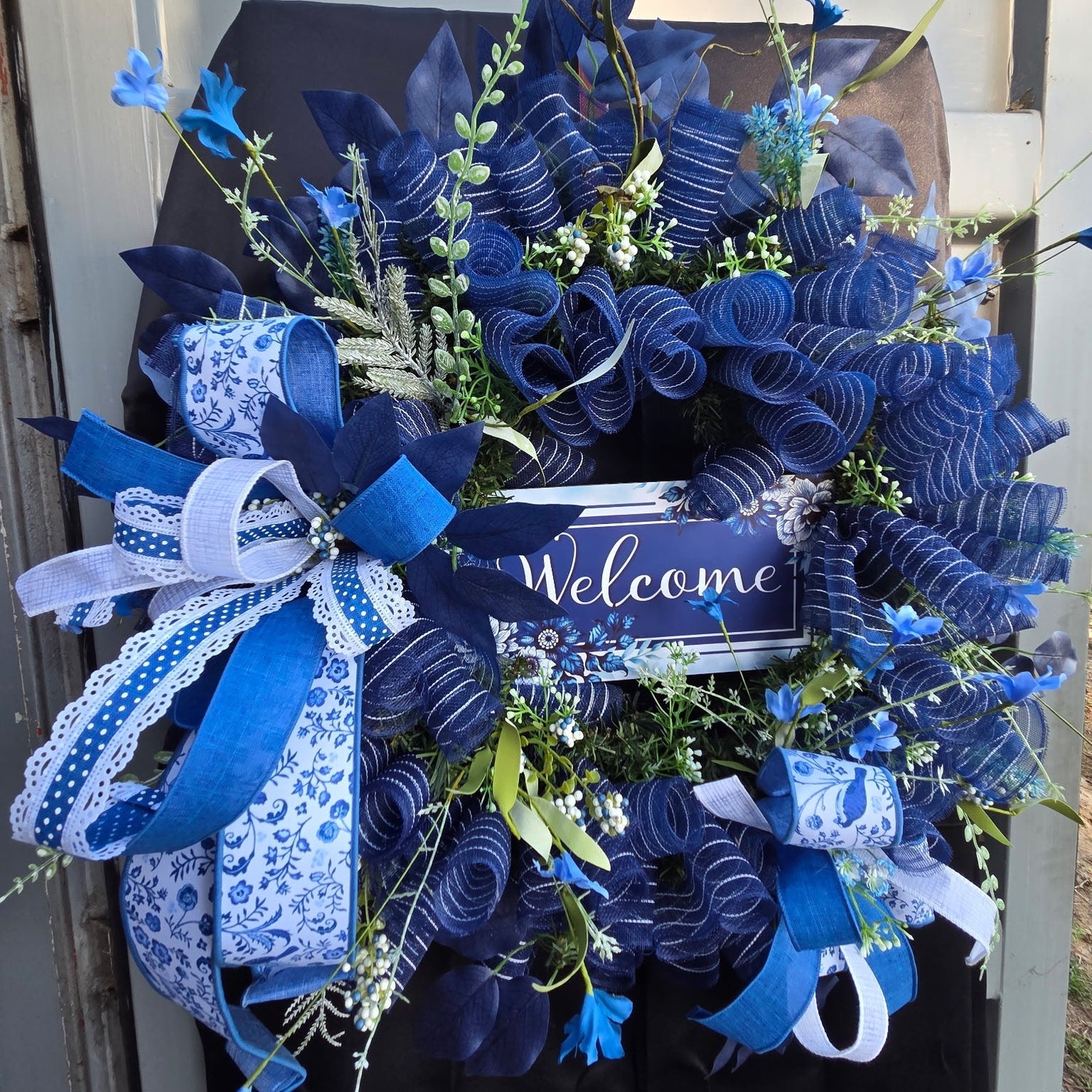 Decorative wreath with blue ribbons and flowers on a door